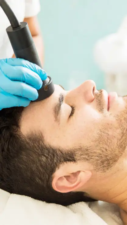Mujer sonriendo sujetando una bonita flor rosa cerca de su cara representando que tiene una buena higiene facial